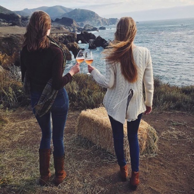 women enjoying the view of the ocean along with a glass of wine