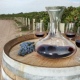 decanter of wine on wine barrel and vineyard in background 